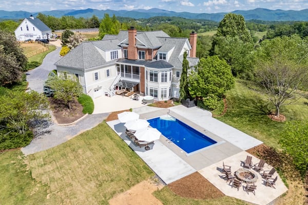 Brick and white colonial home with pool, patio, and mountain views on rural property